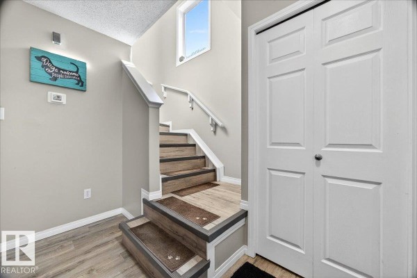 Interior hallway view of stairs going up, double doors, and decorative wall art. - 21339 91 Av Nw, Edmonton