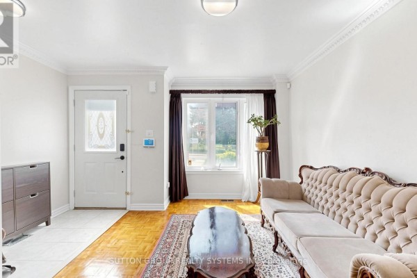 Living room with a light beige sofa, ornate coffee table, rug, and wood floors. - 2138 Eglinton Avenue W, Toronto