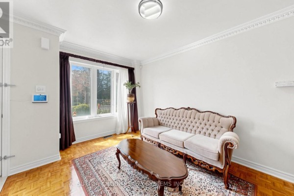 Living room with a tufted sofa, coffee table, patterned rug, and bay window. - 2138 Eglinton Avenue W, Toronto