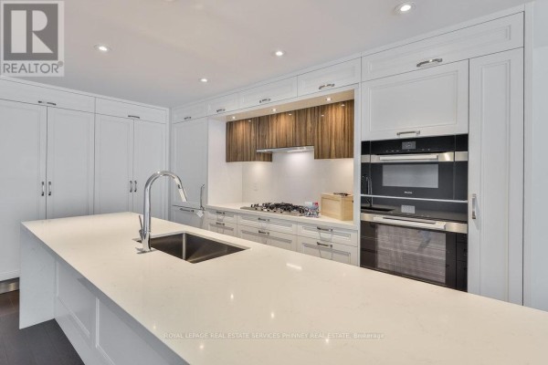 Close-up of the kitchen island with a sink, faucet, and quartz countertop. - 214 - 155 Merchants' Wharf, Toronto