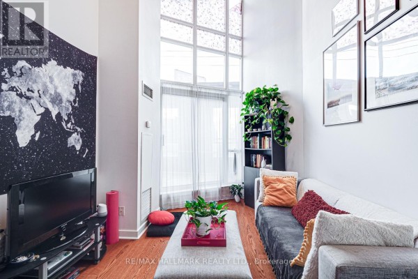 Living room with a sofa, large map tapestry, television, and a floor-to-ceiling window with sheer curtains. - 214 - 255 Richmond Street E, Toronto