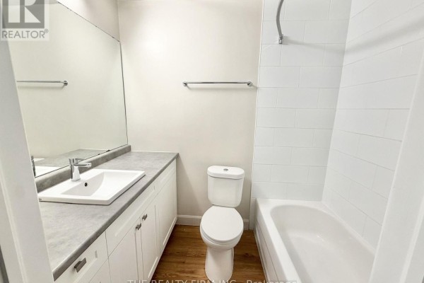 Bathroom with a vanity, toilet, and bathtub with white tiled walls. - 214 - 55 Beechwood Place, London South