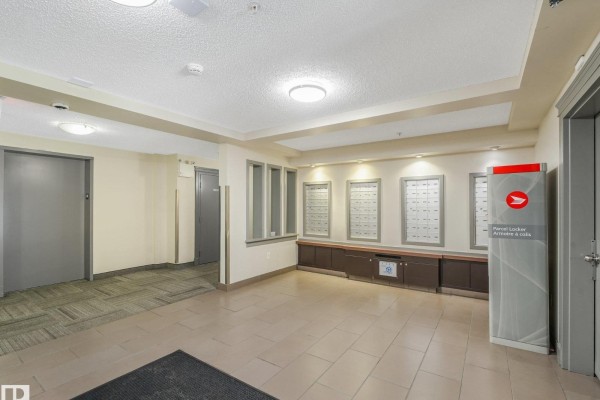 Apartment building lobby with mailboxes, parcel locker, and elevators. - #214 11445 Ellerslie Rd Sw, Edmonton
