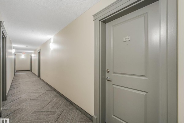 Hallway of apartment building with doors numbered 214 on the right. - #214 11445 Ellerslie Rd Sw, Edmonton