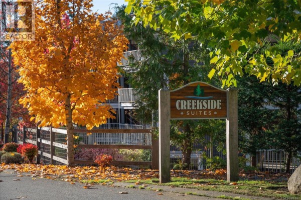 Exterior view of the Creekside Suites apartment building with balconies and autumn trees. - 214 1600 Stroulger Rd, Nanoose Bay