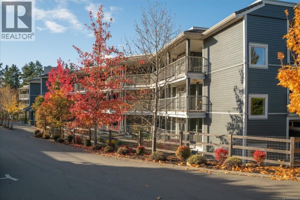 Close-up exterior of the apartment building with balconies and red autumn foliage. - 214 1600 Stroulger Rd, Nanoose Bay
