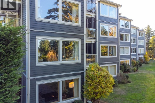 Dark grey siding and large windows on the apartment building exterior. - 214 1600 Stroulger Rd, Nanoose Bay