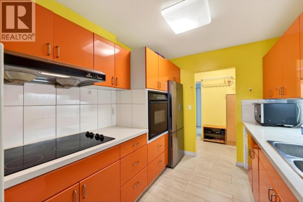 Kitchen with orange cabinets, a stainless steel refrigerator, and white tiled backsplash. - 214 7631 Steveston Highway, Richmond