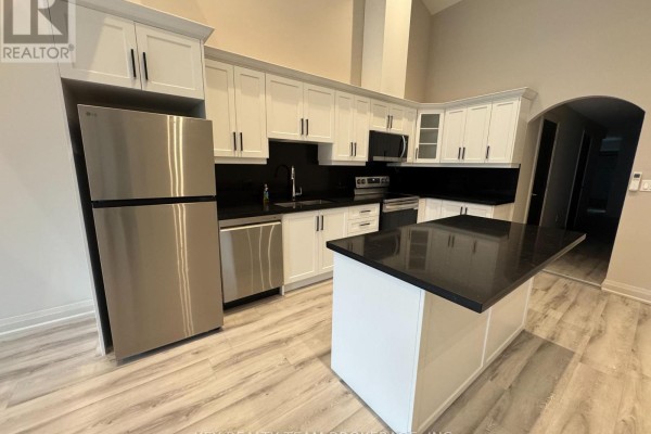 Kitchen with white cabinets, black countertops, stainless steel refrigerator, and an island. - 214 B St Paul Street, St  Catharines