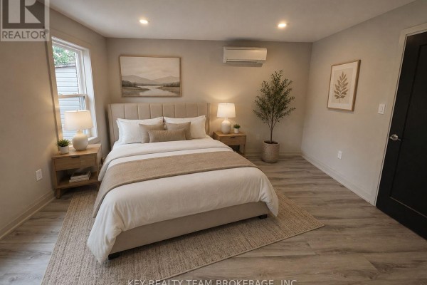 Bedroom with a queen-sized bed, nightstands, air conditioning unit, and a window. - 214 B St Paul Street, St  Catharines