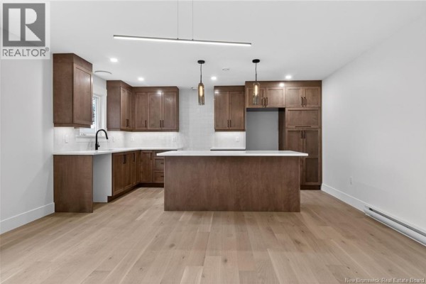 Modern kitchen with dark wood cabinets, white countertops, and an island. - 214 Breaux Bridge Street, Shediac