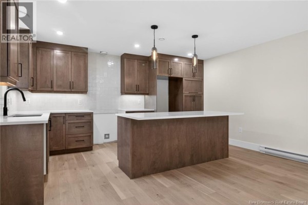 Modern kitchen with dark wood cabinets, white countertops, and an island, showing more of the room. - 214 Breaux Bridge Street, Shediac