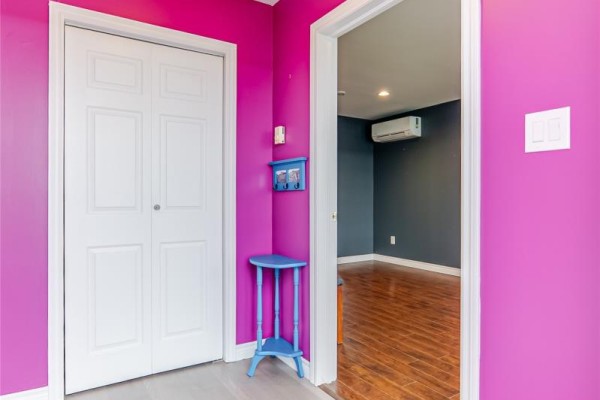 Interior view of a hallway with bright pink walls, white double doors, and a blue accent table. - 214 George Mercer Drive, Bay Roberts