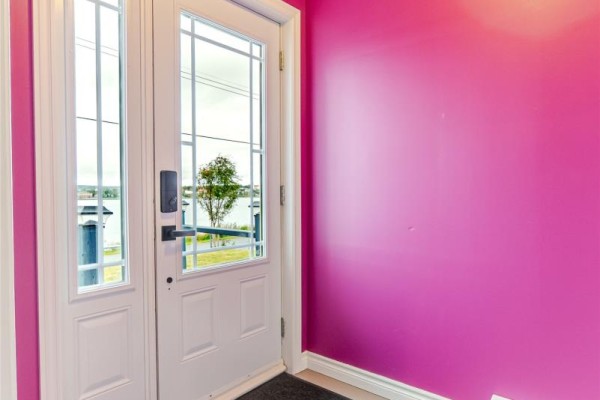 Close-up of a white front door with glass panels, showing a glimpse of the outdoors. - 214 George Mercer Drive, Bay Roberts