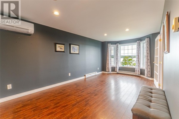 Living room with dark grey walls, dark wood floors, and a large bay window overlooking the water. - 214 George Mercer Drive, Bay Roberts