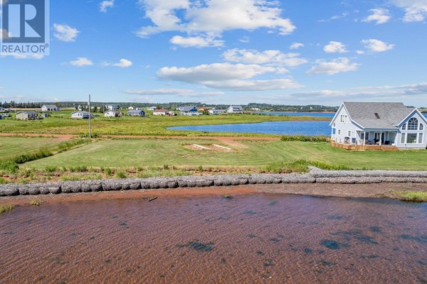 Expansive blue water with a distant sandbar and boats, viewed from a grassy shoreline. - 214 Hebrides Lane, New London, Stanley Bridge