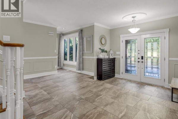 Entrance hall with beige walls, tile floor, and white trim around a window. - 214 Lovers Lane, Ancaster