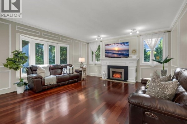 Living room with dark wood floors, a white fireplace, and leather couches. - 214 Lovers Lane, Ancaster