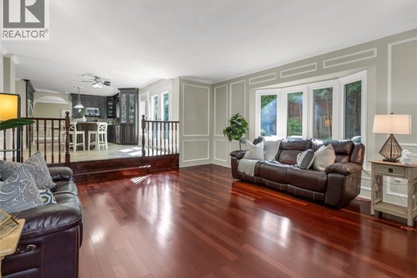 Living room and kitchen area with dark wood floors and a bay window. - 214 Lovers Lane, Ancaster