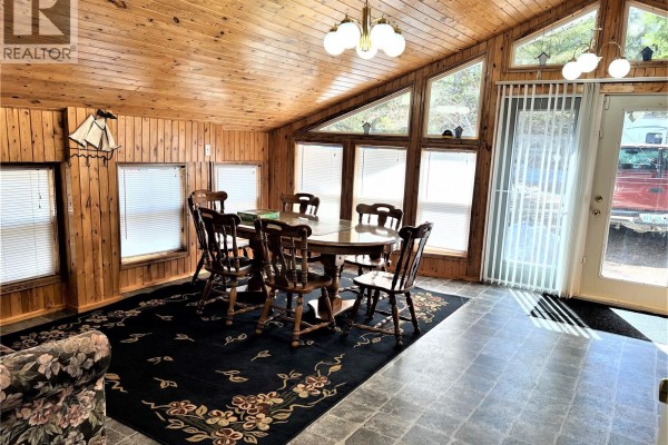 Interior view showing kitchen cabinets, a desk, a piano, and large windows with wood paneling. - 214 Richard Drive, Barrier Lake