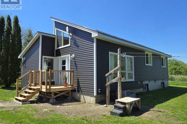Close-up of the front entrance with wooden deck and snow-covered landscape - 2147 Marlbank Road, Tweed)