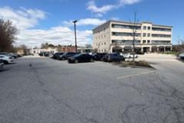 An exterior view of a commercial building with a large parking lot in front. - 215 - 170 The Donway West, Toronto