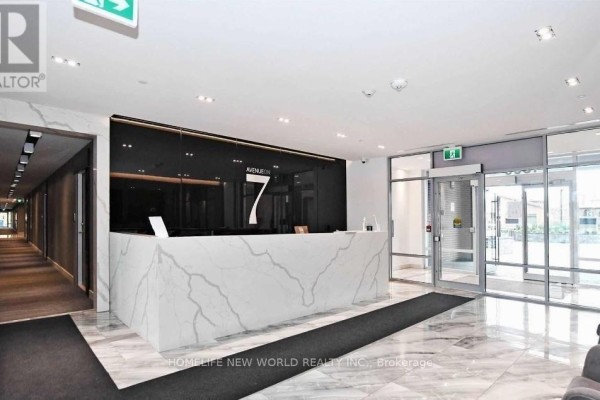 Building lobby with a sleek marble reception desk, glass entrance, and lounge seating. - 215 - 4800 Highway 7, Vaughan