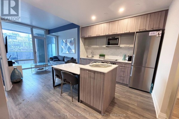 Open concept living and kitchen area with a sofa, dining table, and modern cabinetry. - 215 - 4800 Highway 7, Vaughan