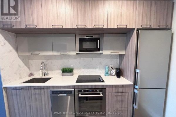 Close-up of the apartment kitchen counter showing a sink, dishwasher, oven, and microwave. - 215 - 4800 Highway 7, Vaughan