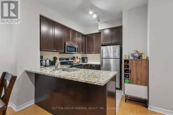 Narrow hallway with a grey sofa, leading to two white doors on either side. - 215 - 9255 Jane Street, Vaughan