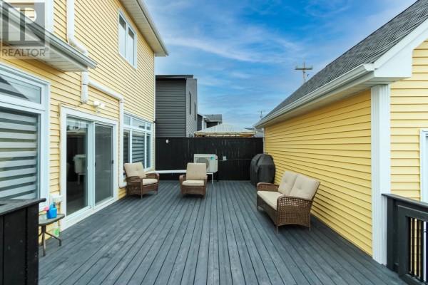 Outdoor seating area on a dark grey deck with wicker furniture and patio doors. - 215 Cheeseman Drive, St  John S