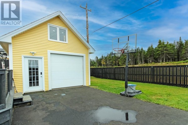 Detached yellow garage with a white door, white garage door, and basketball hoop in the yard. - 215 Cheeseman Drive, St  John S