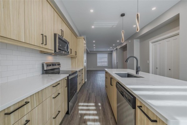 Kitchen with light wood cabinets, stainless steel appliances, white quartz countertops, and island. - 215 Devon Avenue, Winnipeg
