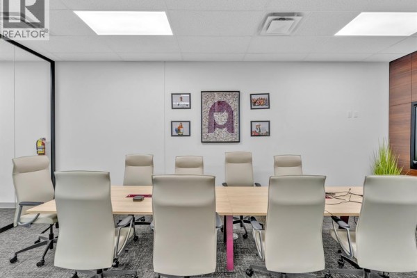 Conference room with beige chairs around a wood table and artwork on the wall. - 215 Eugenie Street West Unit# 101, Windsor