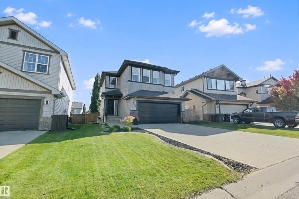 Side exterior view of a two-story house with grey siding and a paved driveway. - 215 Henderson Li, Spruce Grove