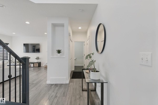 Hallway leading to a washroom and an open-concept living area with a television. - 215 Henderson Li, Spruce Grove