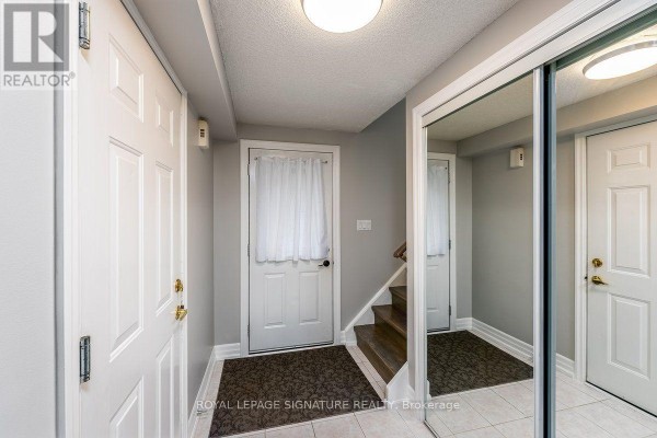 Interior hallway with light grey walls, white doors, tiled floor, and mirrored closet doors. - 215 Turnbridge Road, Barrie