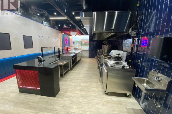 View of the restaurant's cooking area, stainless steel appliances, and a blue tiled backsplash. - 2151 St. Clair Avenue, Toronto