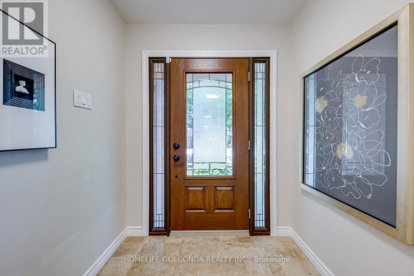 Interior entryway with a wooden front door featuring glass panels and artwork on the wall. - 2152 Munn's Avenue, Oakville