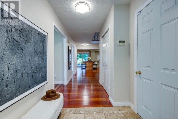 Hallway with polished hardwood floors, white doors, and modern artwork on the left wall. - 2152 Munn's Avenue, Oakville