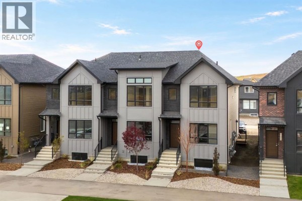 Aerial view of modern townhouses with grey and black siding, dark roofs, and driveway access. - 21527 Sheriff King Street Sw, Calgary