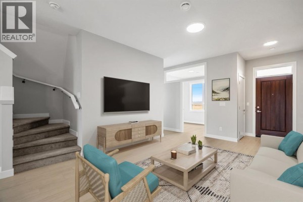 Living room with light grey walls, carpeted stairs, a wood media console, and a beige sofa. - 21527 Sheriff King Street Sw, Calgary