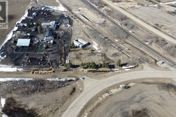 Aerial view of multiple buildings and yards on a property adjacent to railway tracks and a rural road intersection. - 21528a Sec Hwy  617, Rural Camrose County