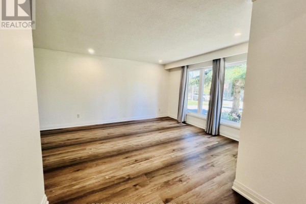 Living room with light-colored walls, dark wood laminate flooring, and large windows with grey curtains. - 2154 Adullam Avenue, Innisfil