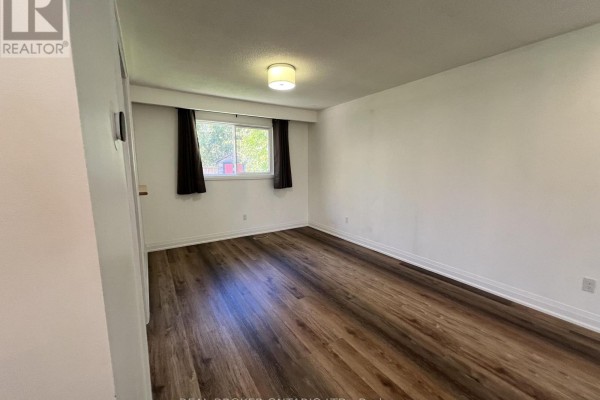 Bedroom with white walls, dark wood laminate flooring, and a window with black curtains. - 2154 Adullam Avenue, Innisfil