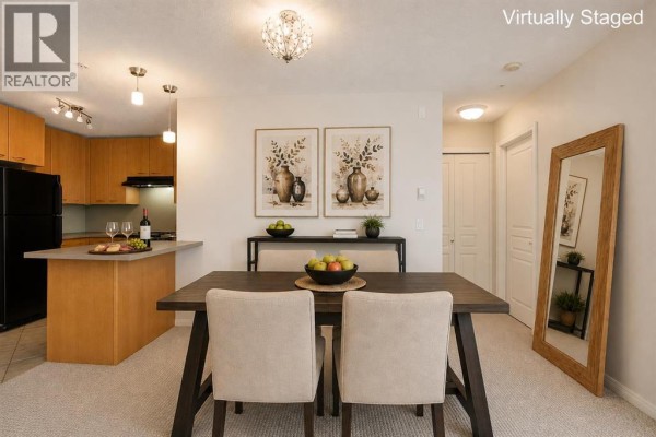 Apartment kitchen with light wood cabinets, stainless steel appliances, and a view of the dining area. - 216, 5115 Richard Road Sw, Calgary