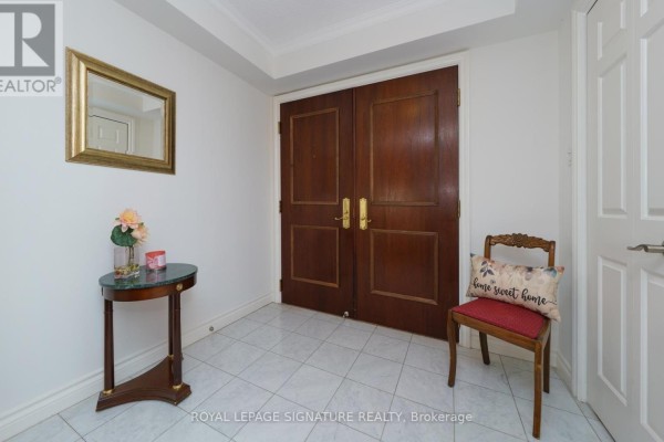 Foyer with tiled floor, a dark wood double door entrance, a small round table, and a mirror. - 216 - 215 The Donway West W, Toronto
