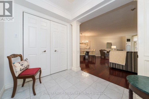 View from the foyer into the dining and living room area with dark wood floors. - 216 - 215 The Donway West W, Toronto