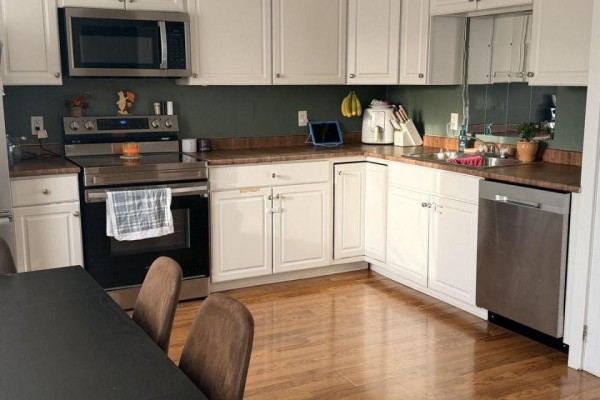 Corner kitchen with white cabinets, stainless steel appliances, and wood countertops. - 216 - 220 Erie Street, Port Colborne