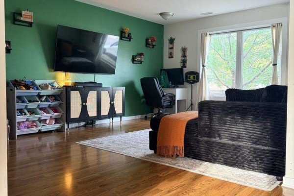 Living room with a large television, black furniture, and hardwood floors. - 216 - 220 Erie Street, Port Colborne
